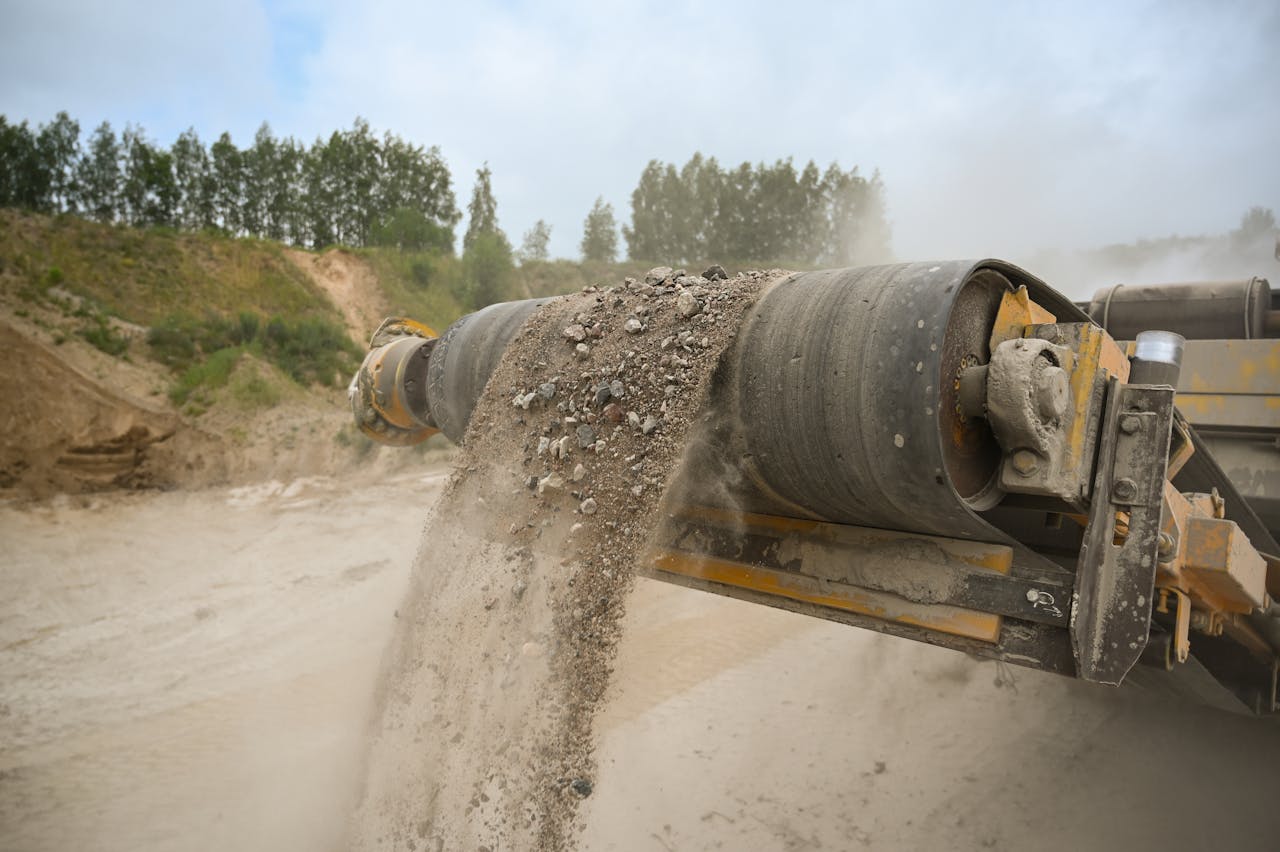 A close-up of an industrial conveyor belt moving gravel at a construction site