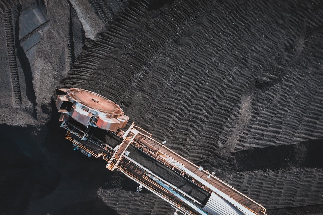 From above of industrial machine with conveyor belts digging and transporting coal in daylight
